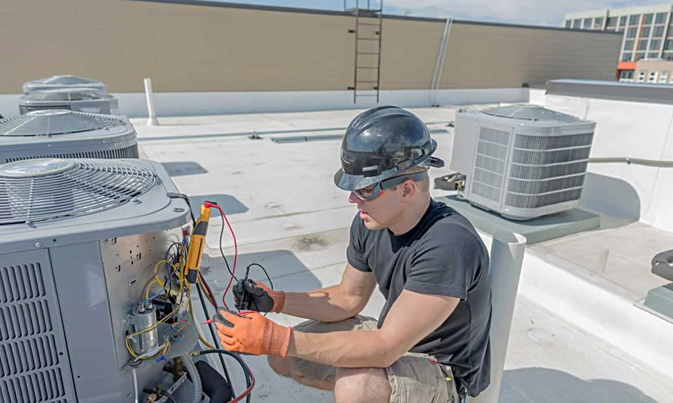 HVAC technician servicing rooftop cooling equipment in a city setting
